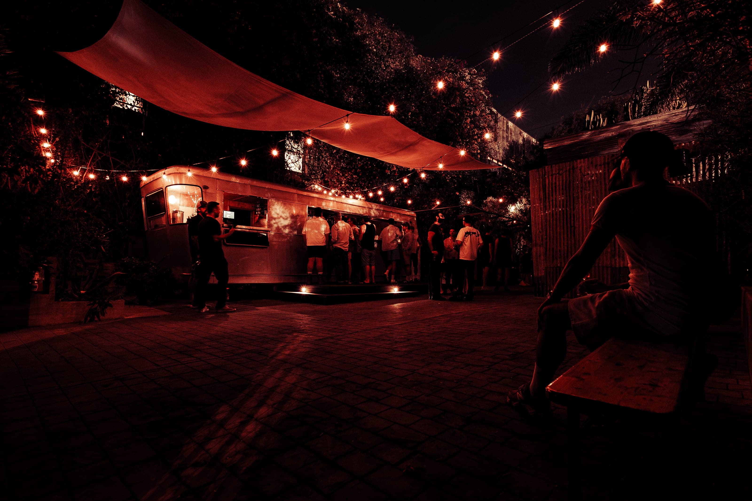 Guests lined up at the vintage trailer bar in Animal LA's string-lit courtyard at night, a canopy overhead
