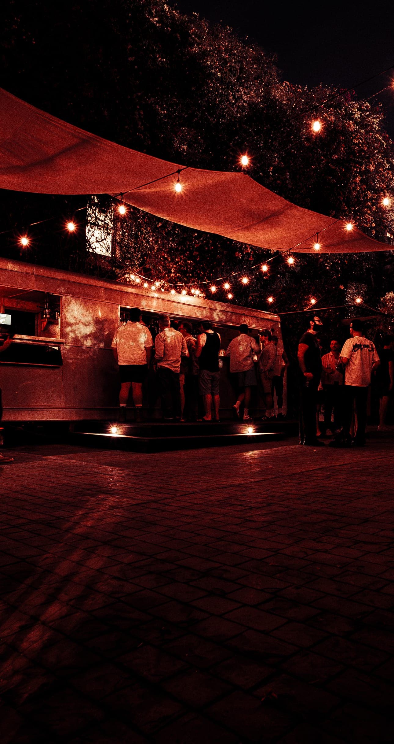 Guests lined up at the vintage trailer bar in Animal LA's string-lit courtyard at night