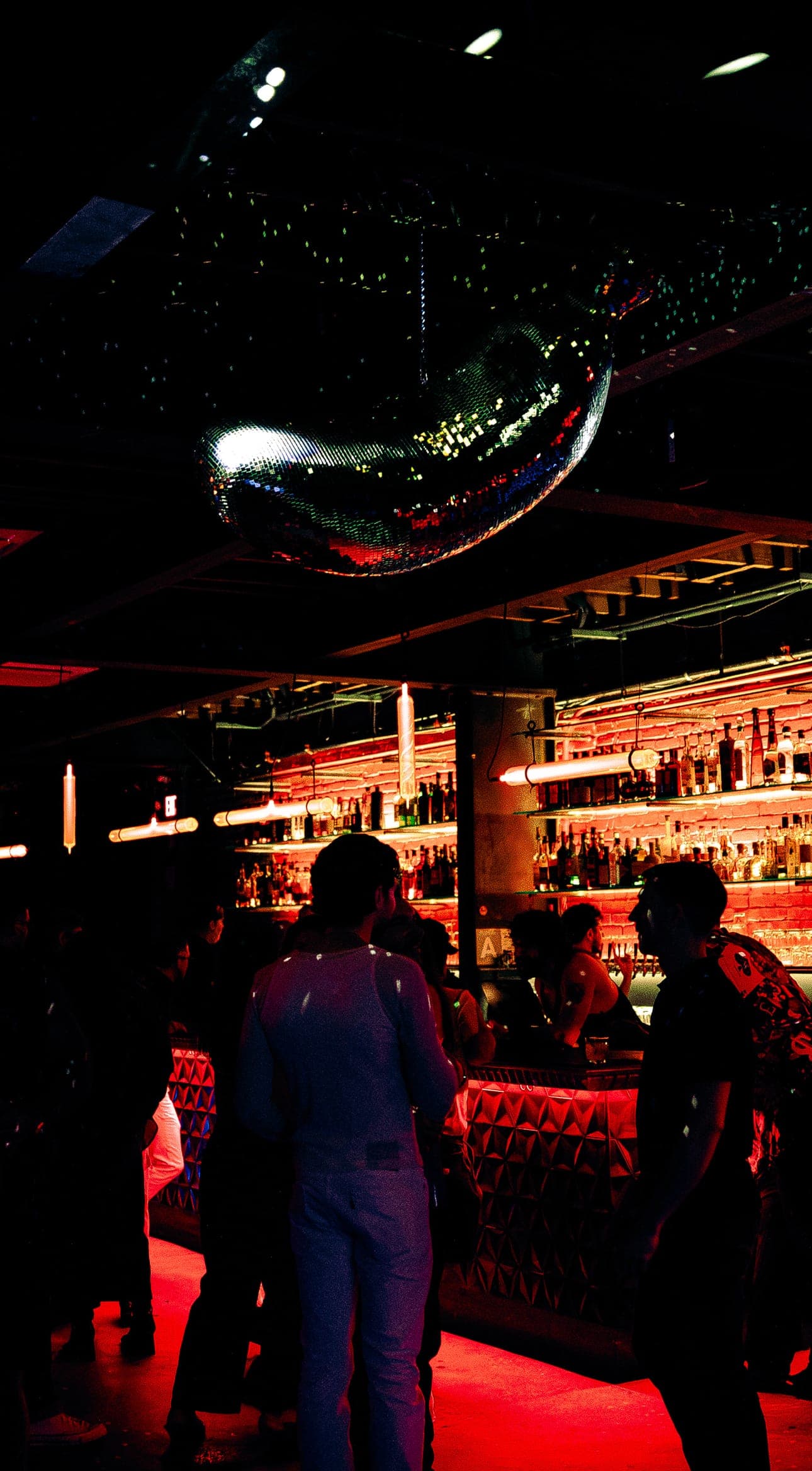 A mirrored disco ball above the dim main room, with guests gathered at the bar